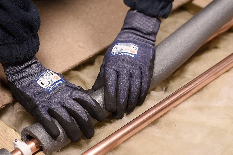 A person lagging pipes with foam insulation in a loft