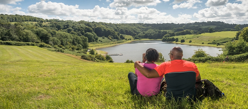 Couple sat in field overlooking Clatworthy Reservoir