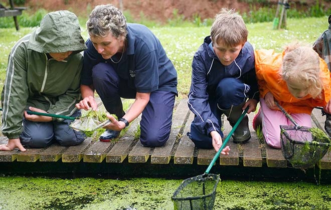 Education adviser Sue with school children fishing in a pond