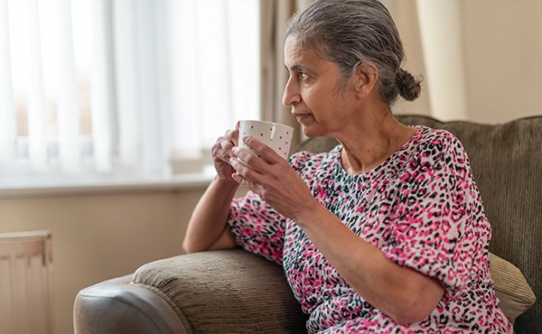 Elderly customer sat in an armchair with a cup of tea